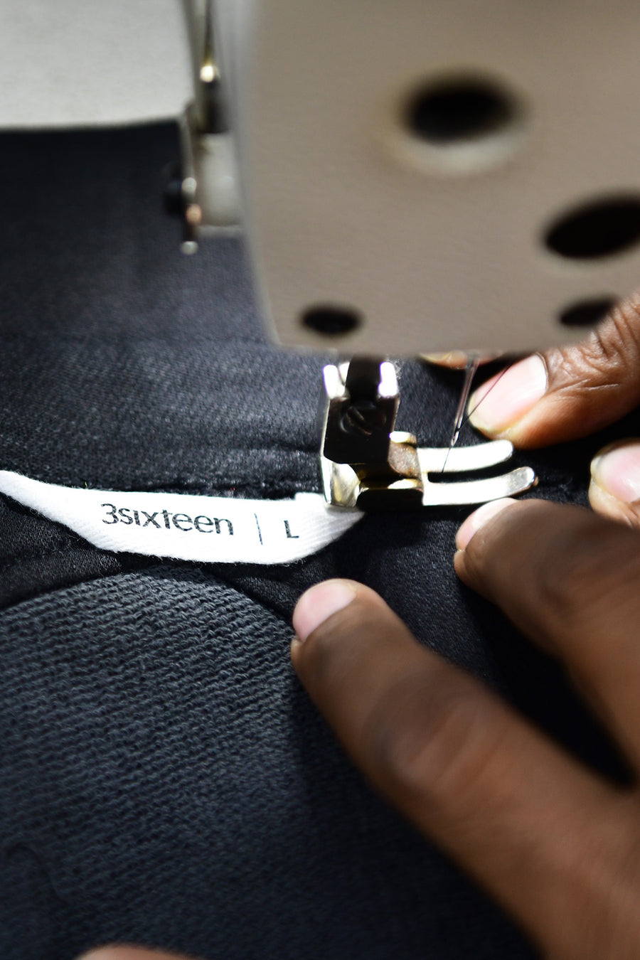 A man sews a 3sixteen shirt at a sewing machine.
