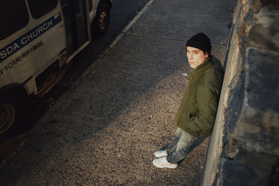 The model looks up into the camera while wearing the olive down jacket.