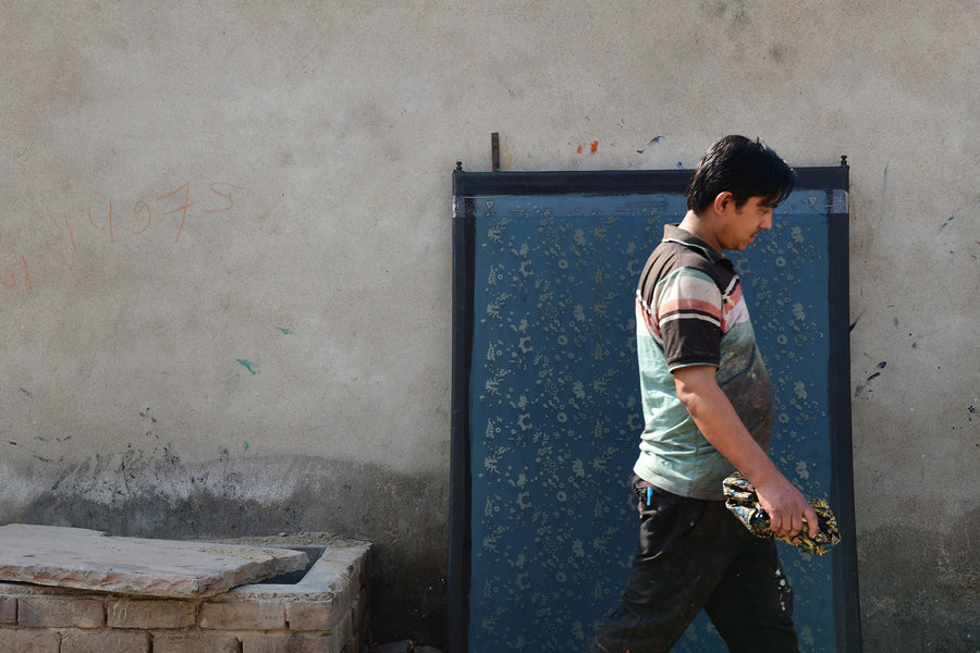 A man walks past a large silk screen.