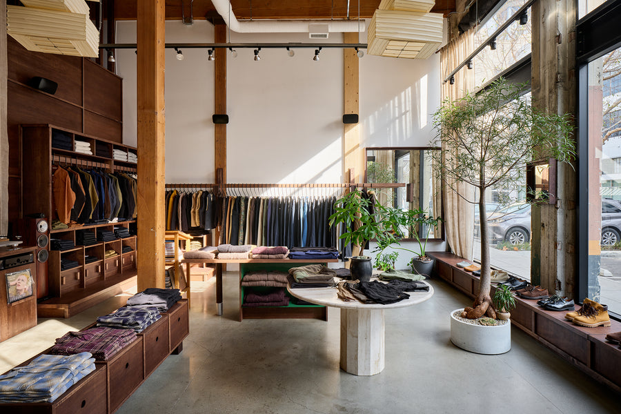 A wide angle view of the store shows a long wooden rail with jeans hanging on it.
