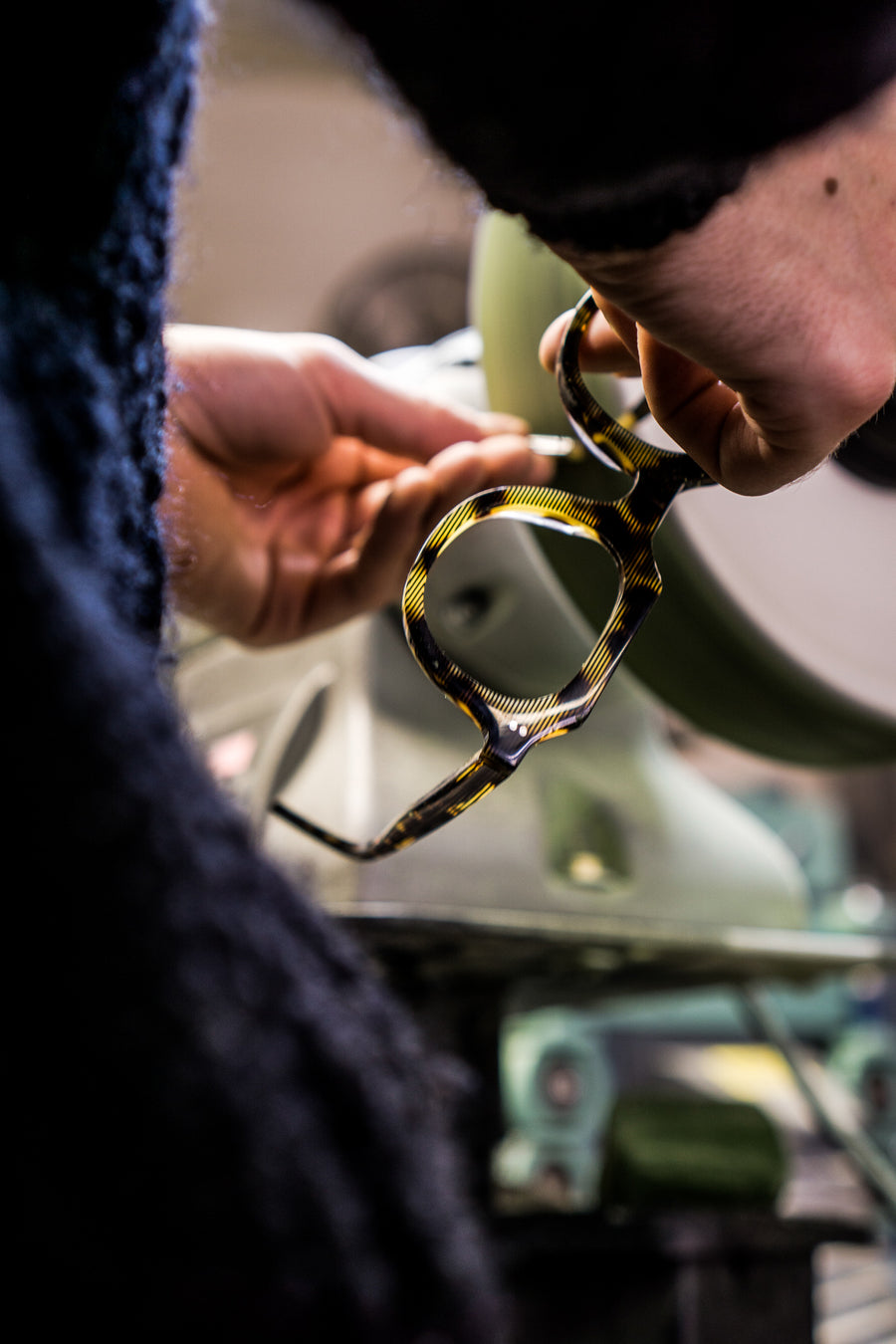A man polishes a set of eyeglass frames on a machine.