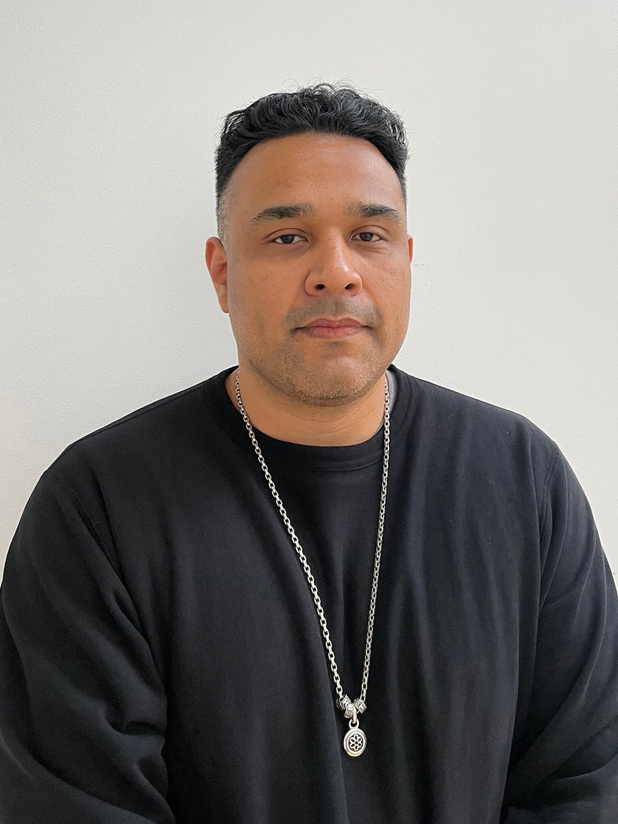 A very handsome man in a black tee and a silver necklace.