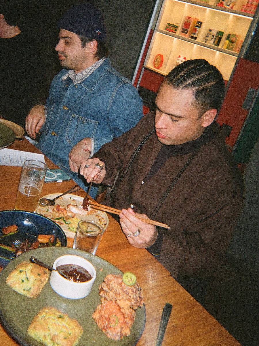 A man with braids eating food in a restaurant.