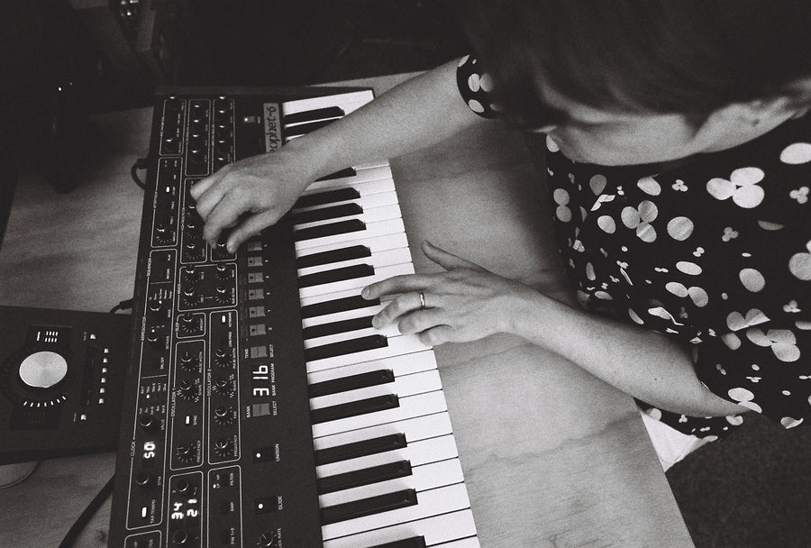 A man plays the keyboard in a black shirt with white dots.