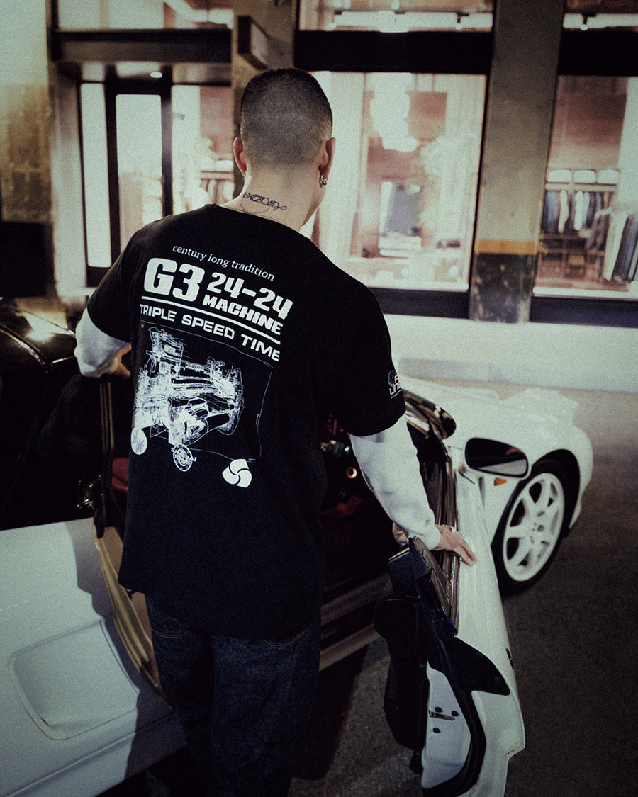 A man in a black graphic tee gets into the drivers seat of a RHD car.