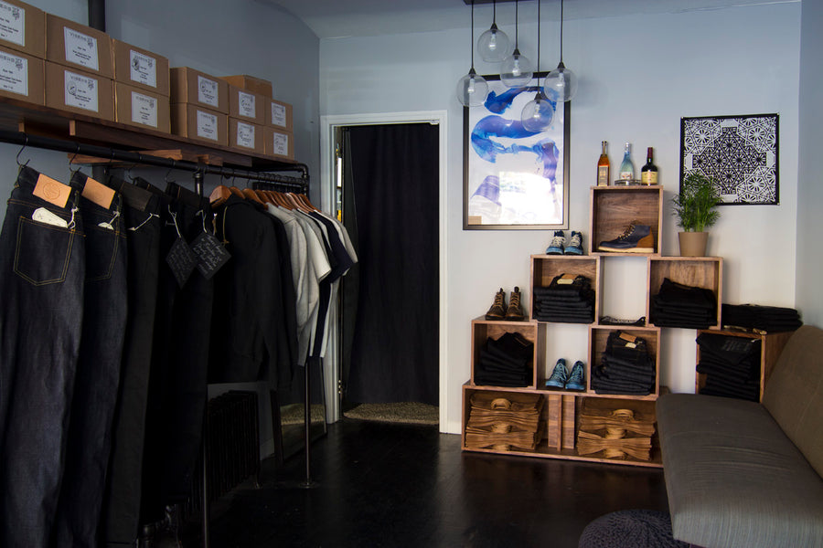 Jeans hang on a black rack with boot boxes stacked above in the 3sixteen 10 year anniversary pop up shop.