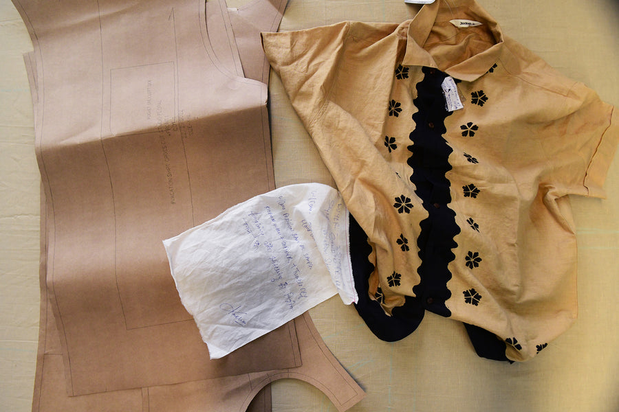 A block printed shirt sits on a printing table with patterns and a hand written note.