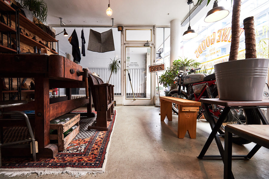 A shot of a beautiful retail store with worn in wood tables and natural light.