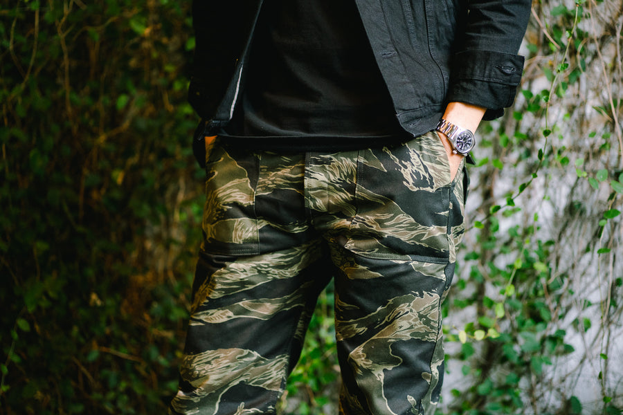 A top block shot of the camouflage pants against a wall of greenery