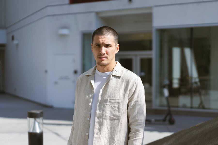 A young man in a linen shirt looks into the camera.