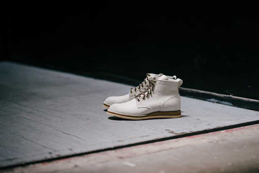 A pair of white Viberg boots stand in an elevator shaft.