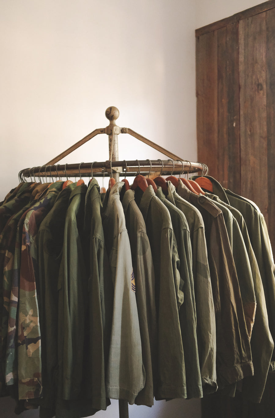 A myriad of olive army jackets hang on a circular rack.