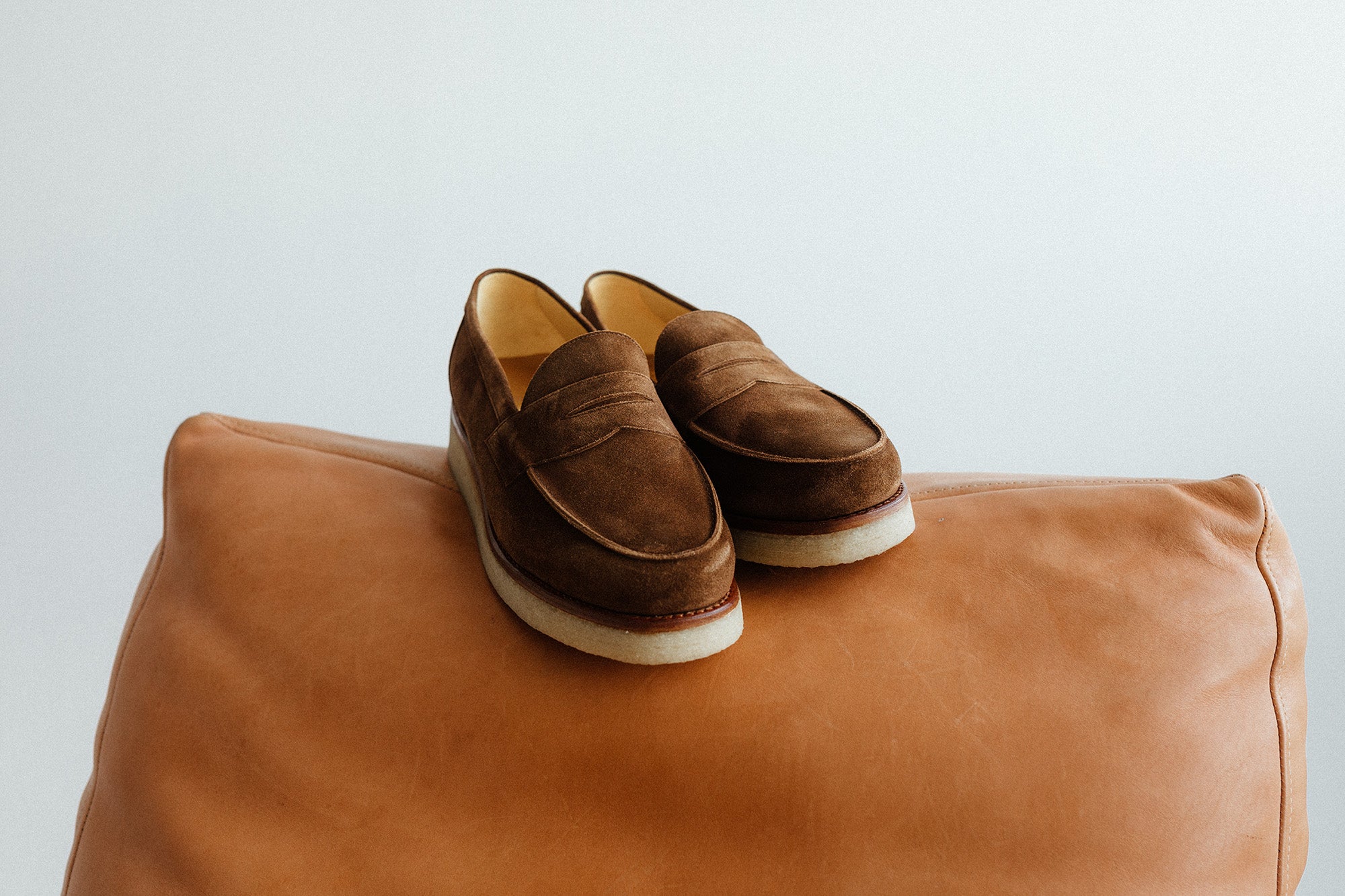 A pair of brown loafers on a leather couch.