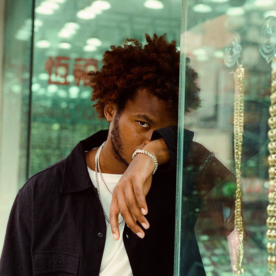 A man stands outside a jewelry store with white gold chains and bracelet on.