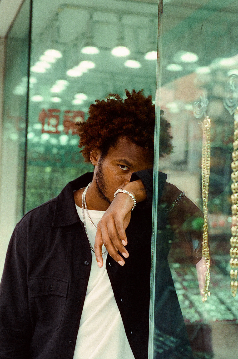 A man stands outside a jewelry store with white gold chains and bracelet on.