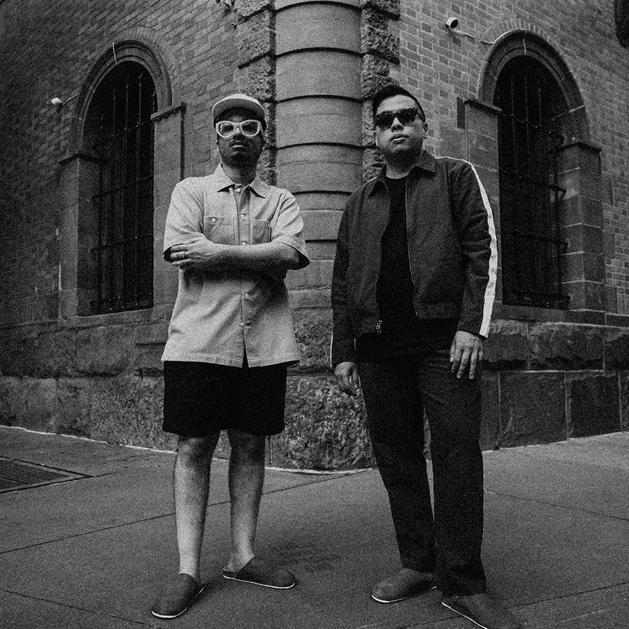 Two guys stand on a street corner in mules