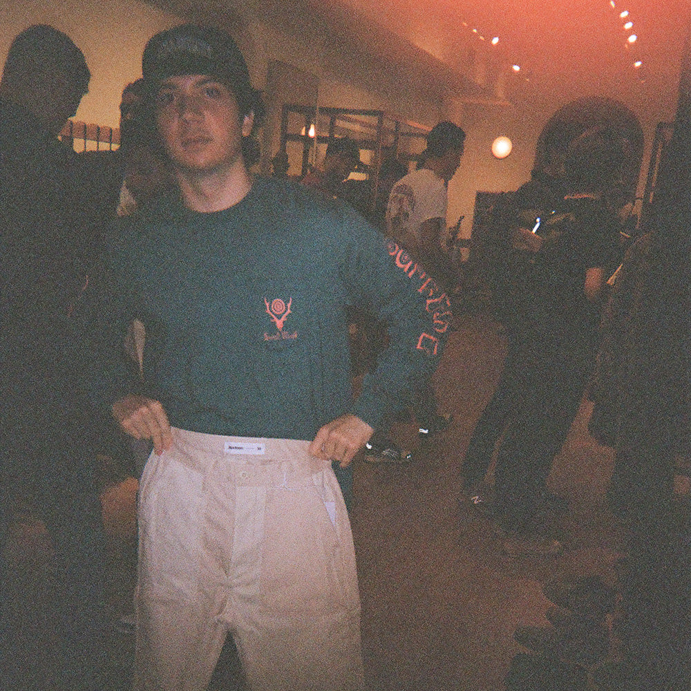 A young man holds up a pair of the podcast pants.