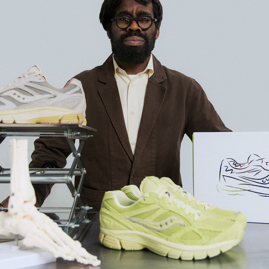 A man stands with two pairs of Saucony sneaker on a table.