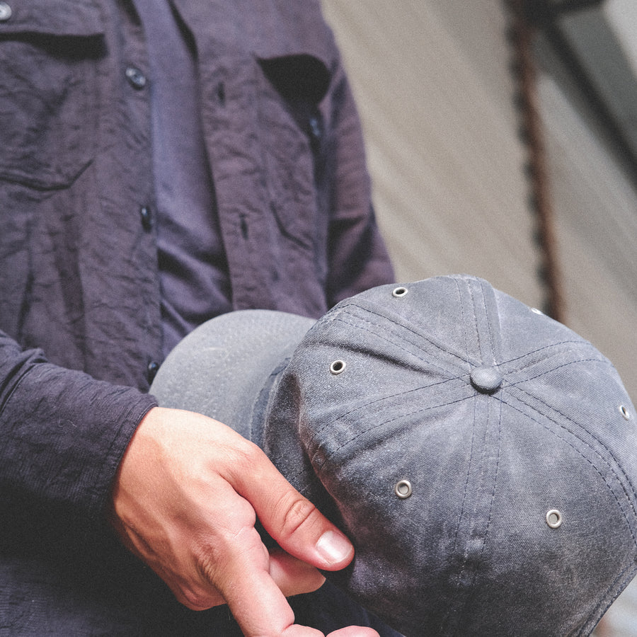 A waxed canvas baseball cap held in hand.