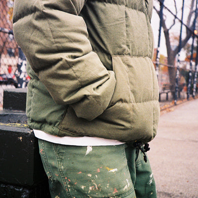A close up shot of a paneled olive down jacket made of vintage army materials.