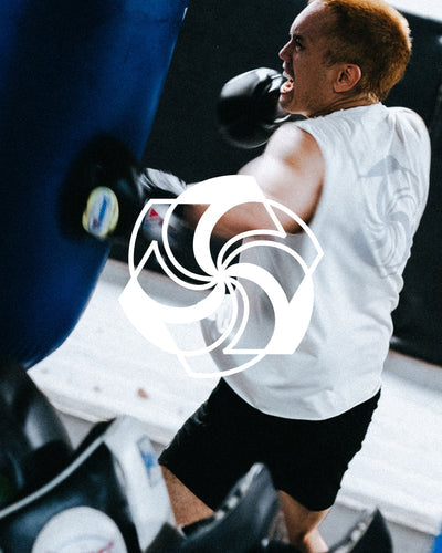 A man in a white tee punches a blue punching bag.