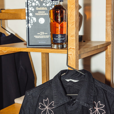 A photo of the 29 year old scotch next to a black denim jacket.