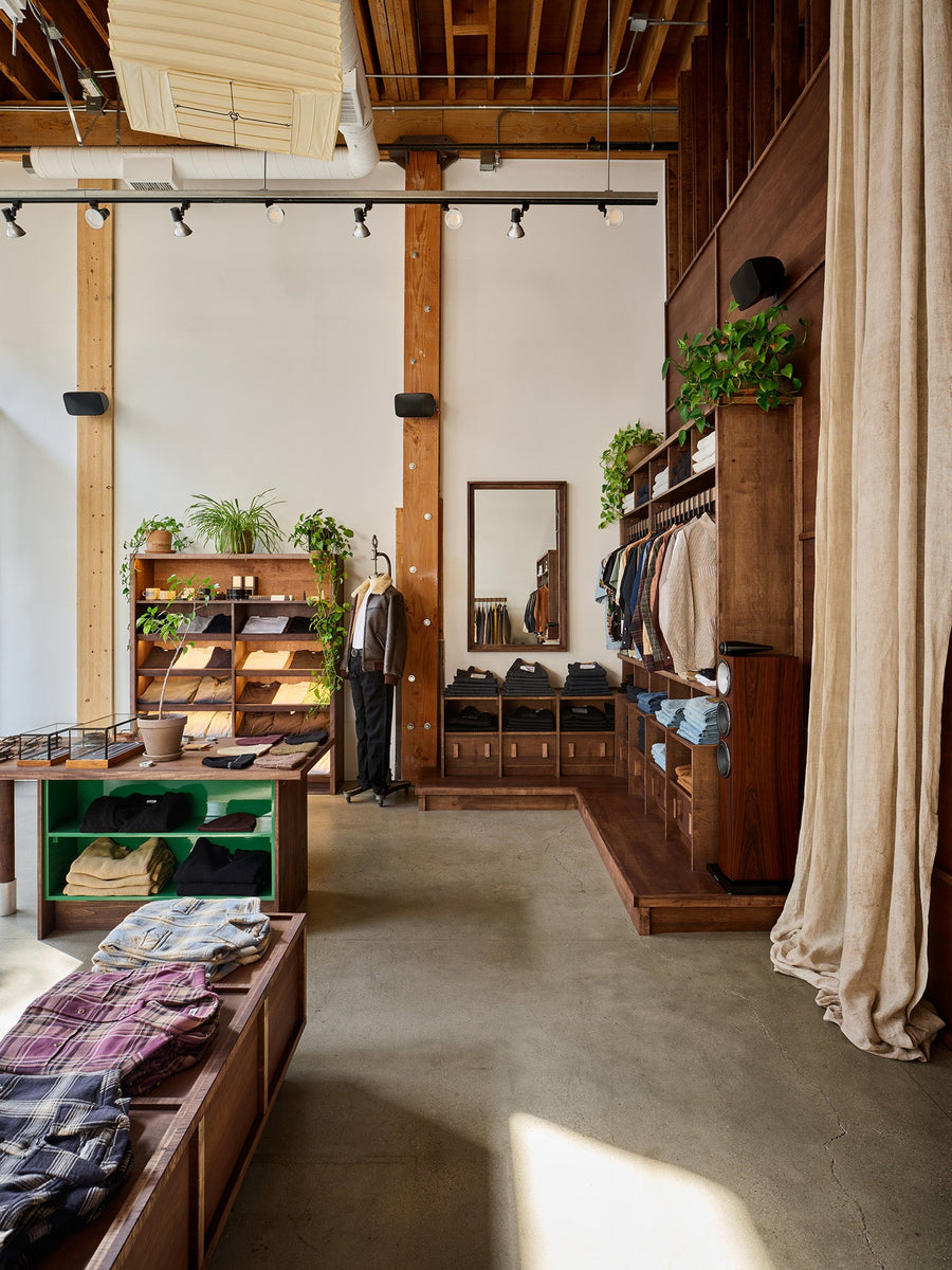 A storefront with plants on shelves and dark wood fixtures.