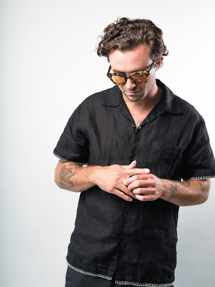 A man wears sunglasses and a black shirt.