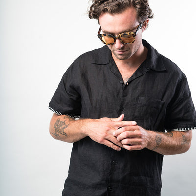 A man wears sunglasses and a black shirt.