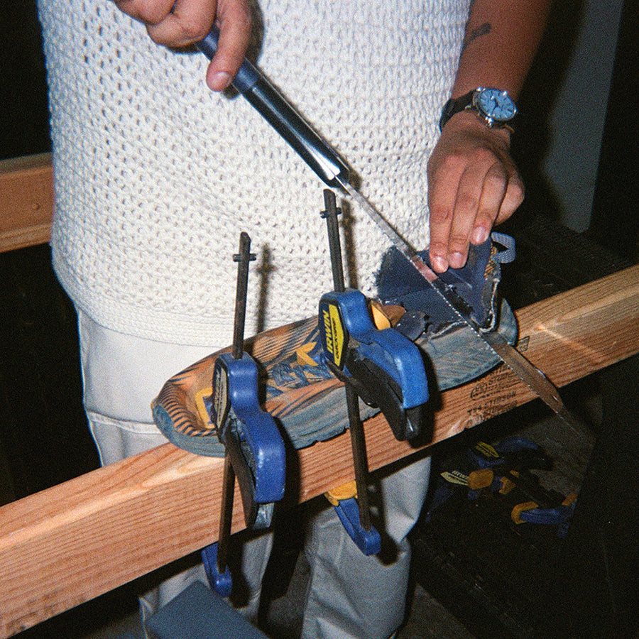 A man saws a shoe heel off.