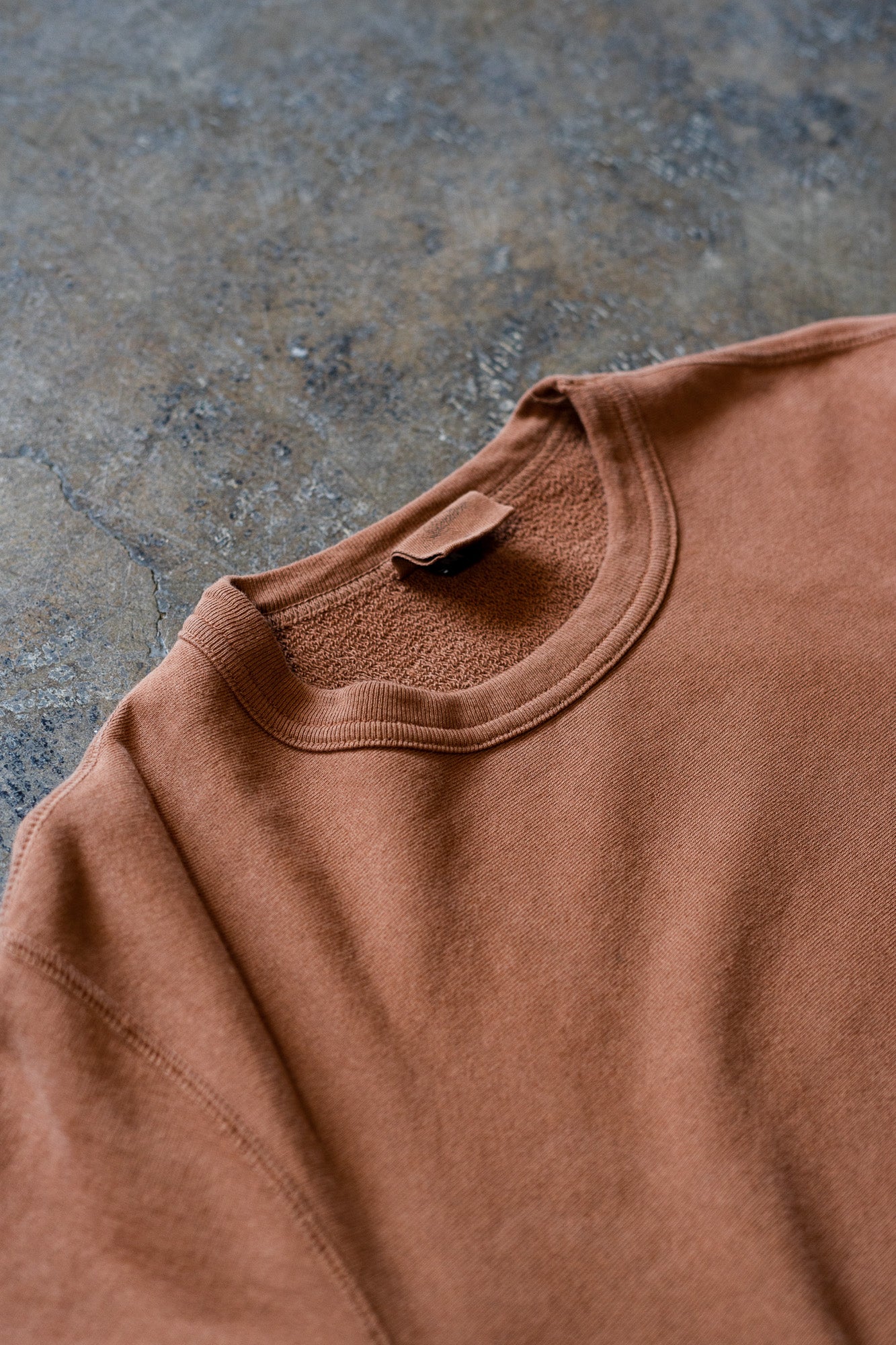 A close up view of the clove crewneck sweatshirt lying on the ground.