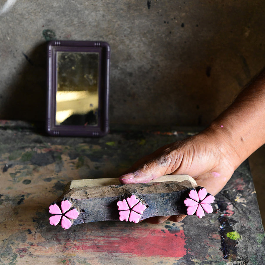 Someone holds a wooden block with sakura blossoms carved into it.