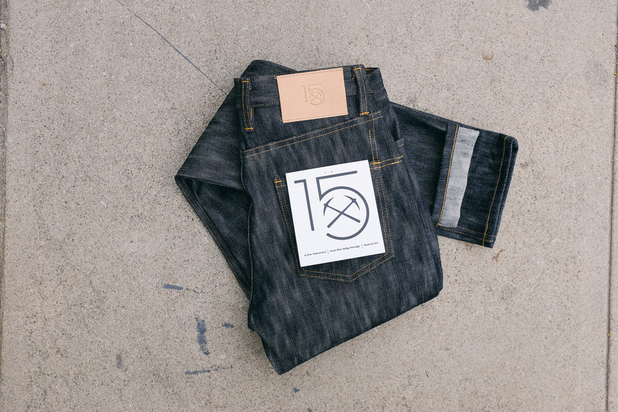 The 15y denim lays folded on the ground, showing a white pocket flasher with our 15y logo printed on it.