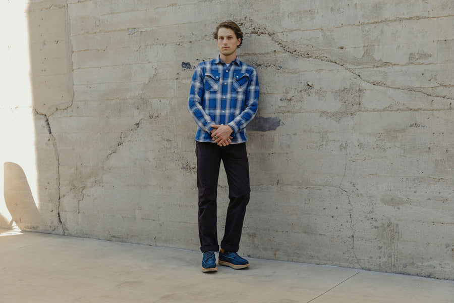 The model wears a blue check 3sixteen flannel with his arms crossed in front of his body.