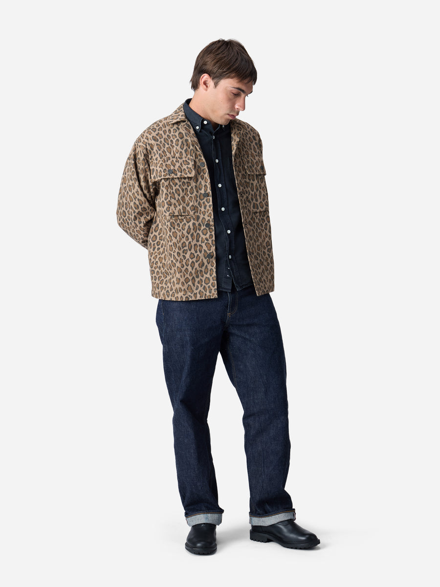 Man wearing a leopard print jacket, dark shirt, and jeans on a white background