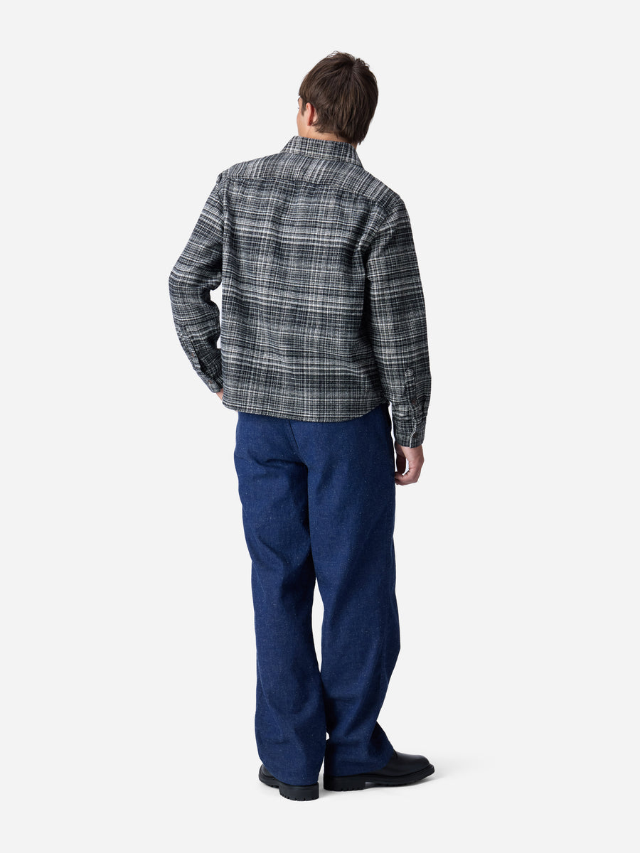Person wearing a plaid shirt and blue pants on a white background