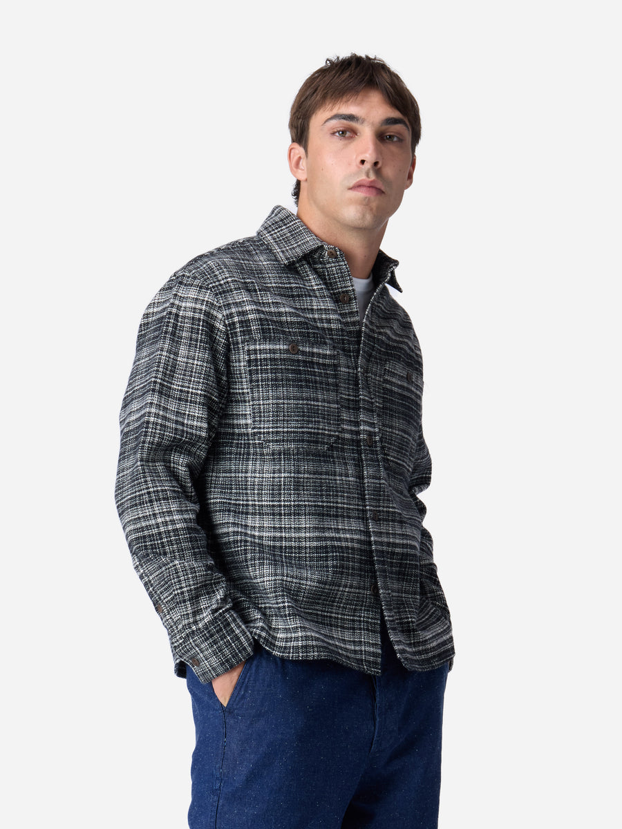 Man wearing a plaid shirt and blue pants on a white background