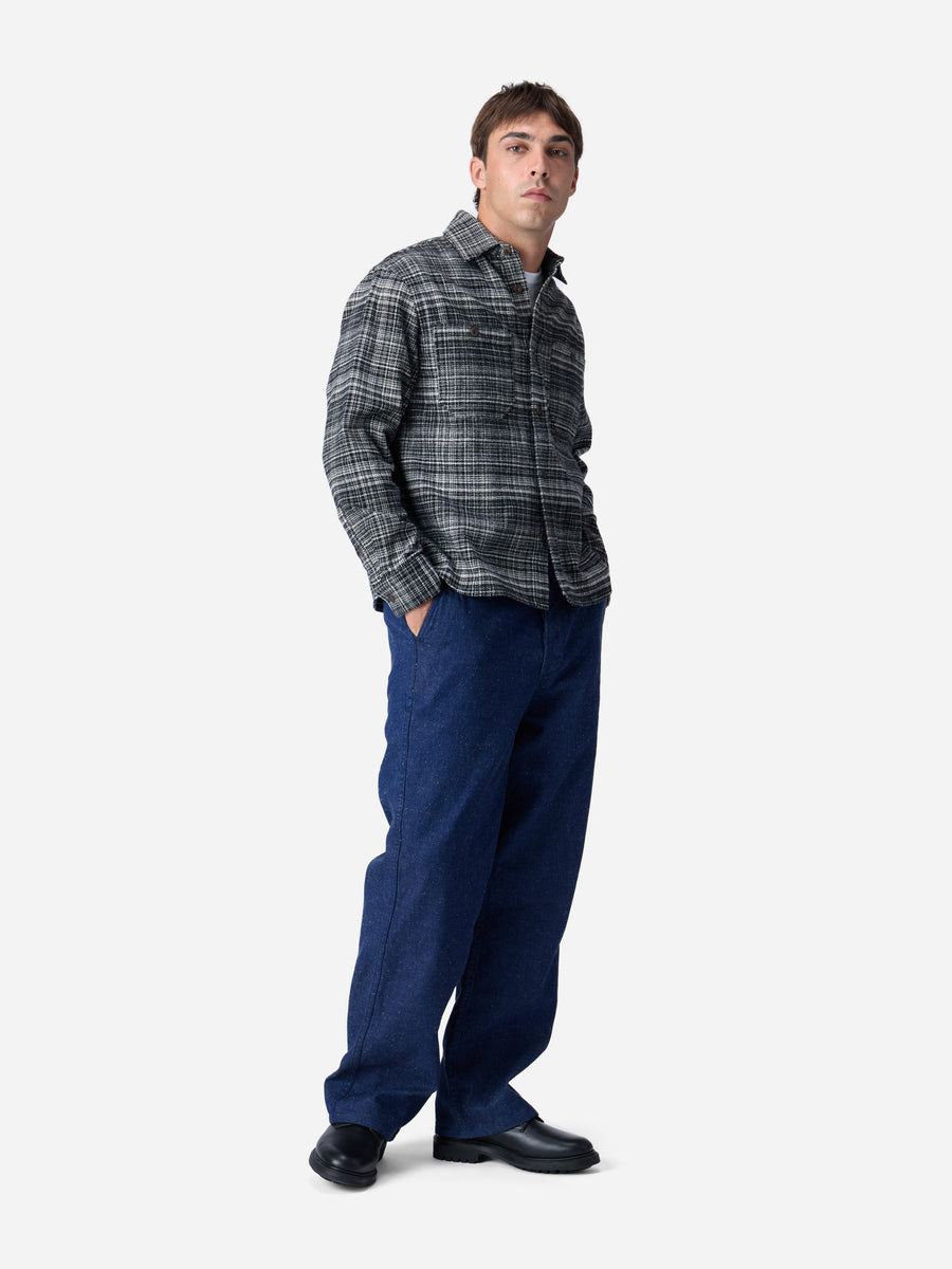 Man wearing a plaid shirt and blue pants on a white background