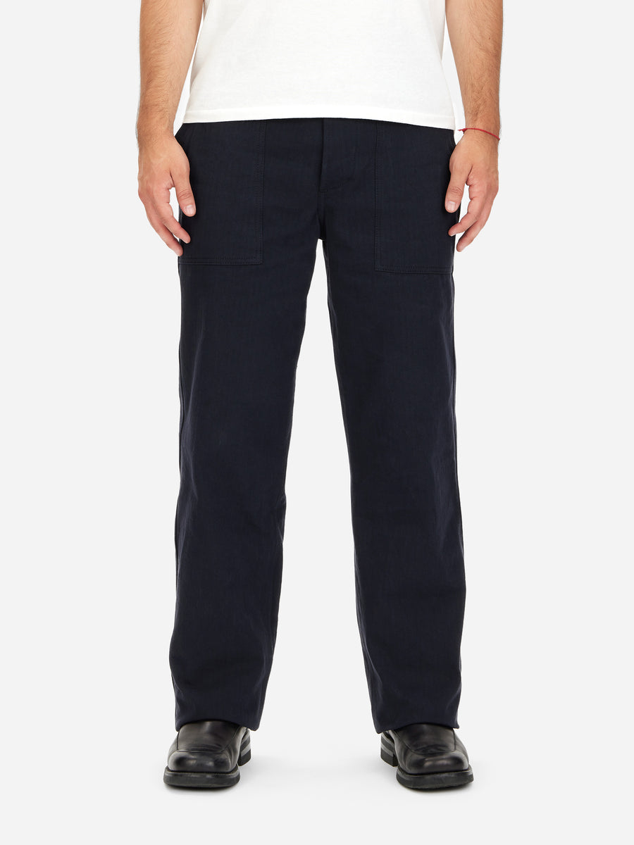 A person standing, wearing the Fatigue Pant in a midnight washed HBT fabric, displaying a straight leg military pant silhouette.