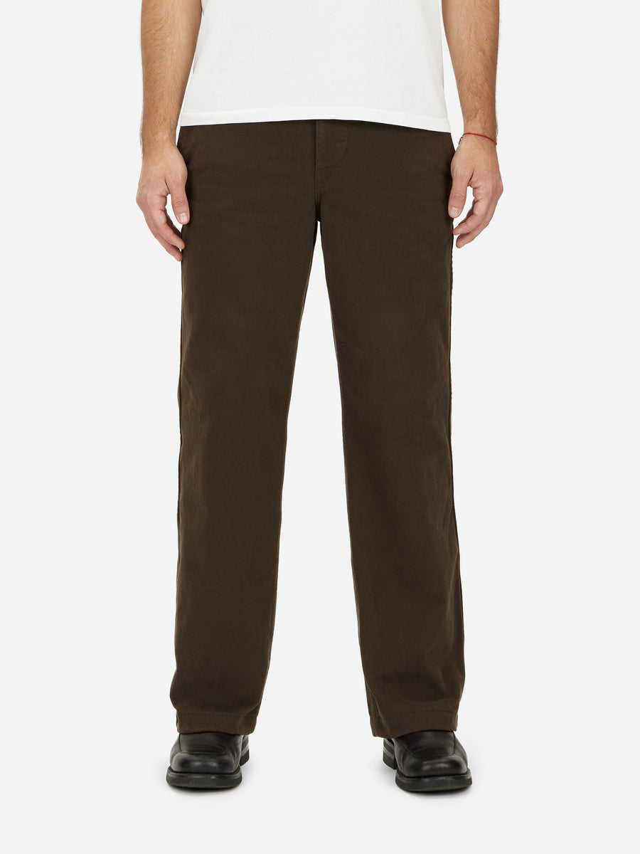 A person standing, wearing a pair of brown wide leg work pants with high rise, made of chino twill fabric.