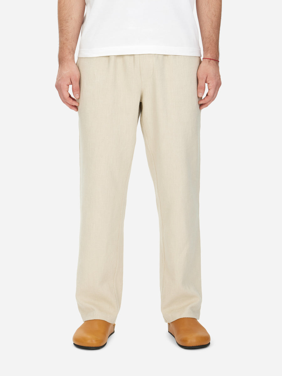 A pair of beige cotton/linen blend easy pants with an elastic drawstring waistband, straight leg, and reinforced rear patch pockets.