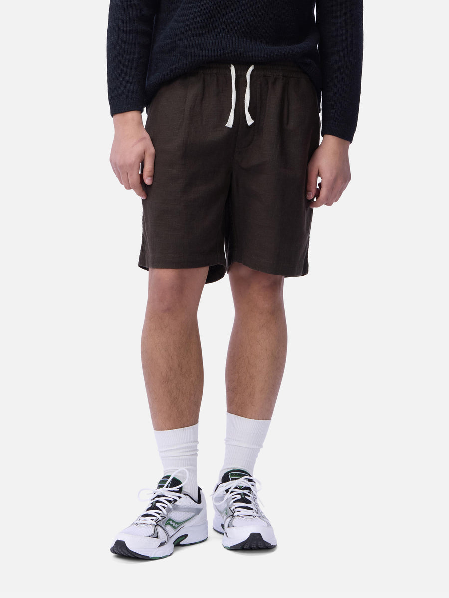 Person wearing dark brown shorts, a navy sweater, white socks, and white sneakers on a white background