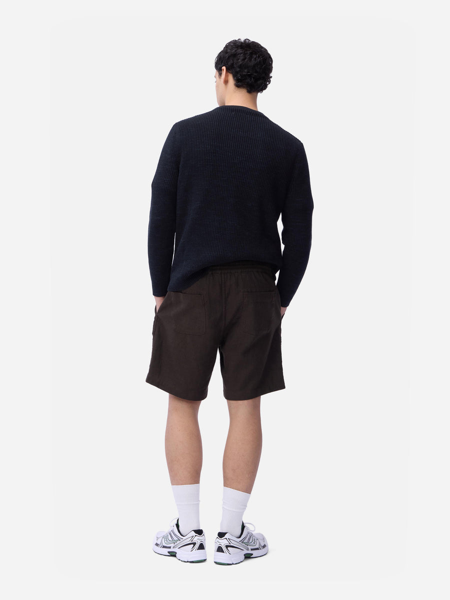 Person wearing a black sweater and brown shorts on a white background