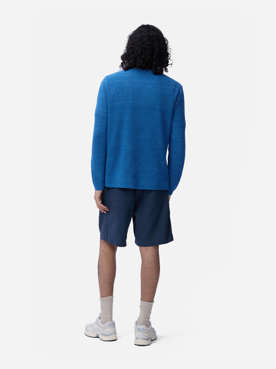 Person wearing a blue sweater and shorts on a white background