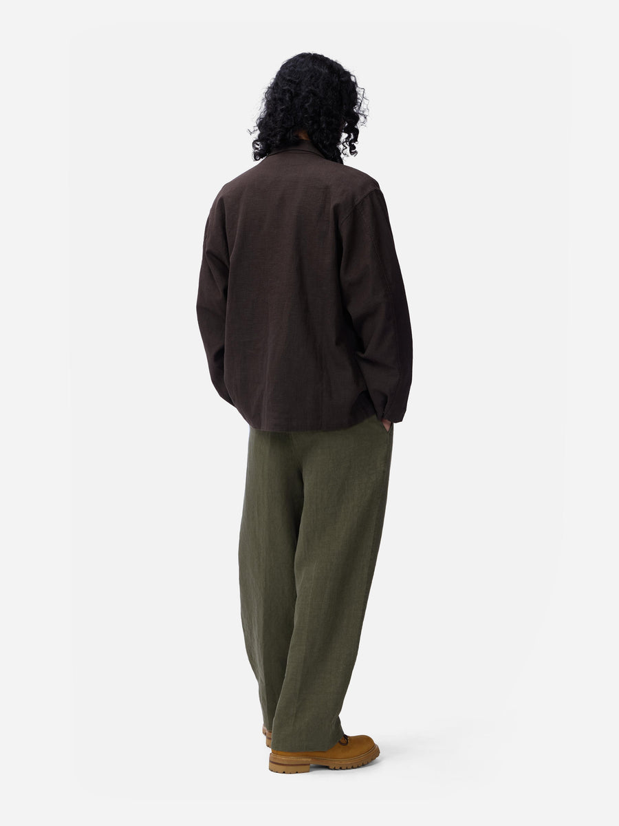 Person wearing a dark jacket and green pants on a white background