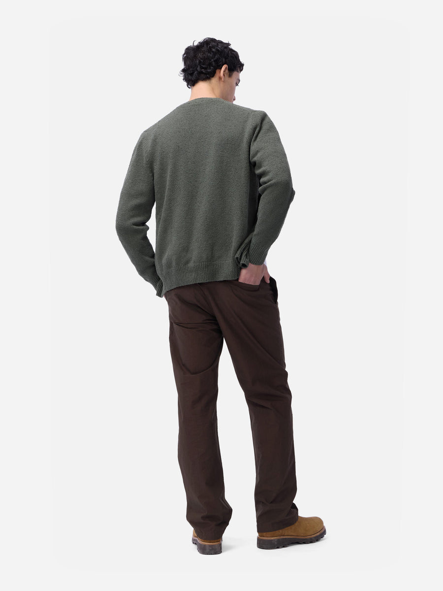 Man wearing a green sweater and brown pants on a white background