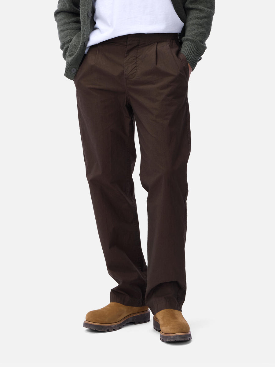 Person wearing brown pants and brown shoes on a white background