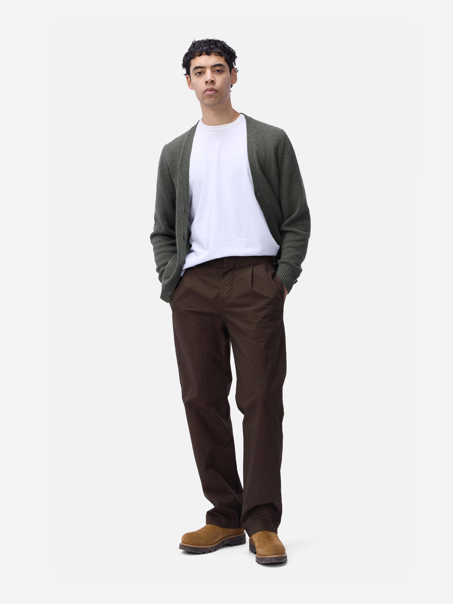 Man wearing a green cardigan, white shirt, brown pants, and brown shoes on a white background