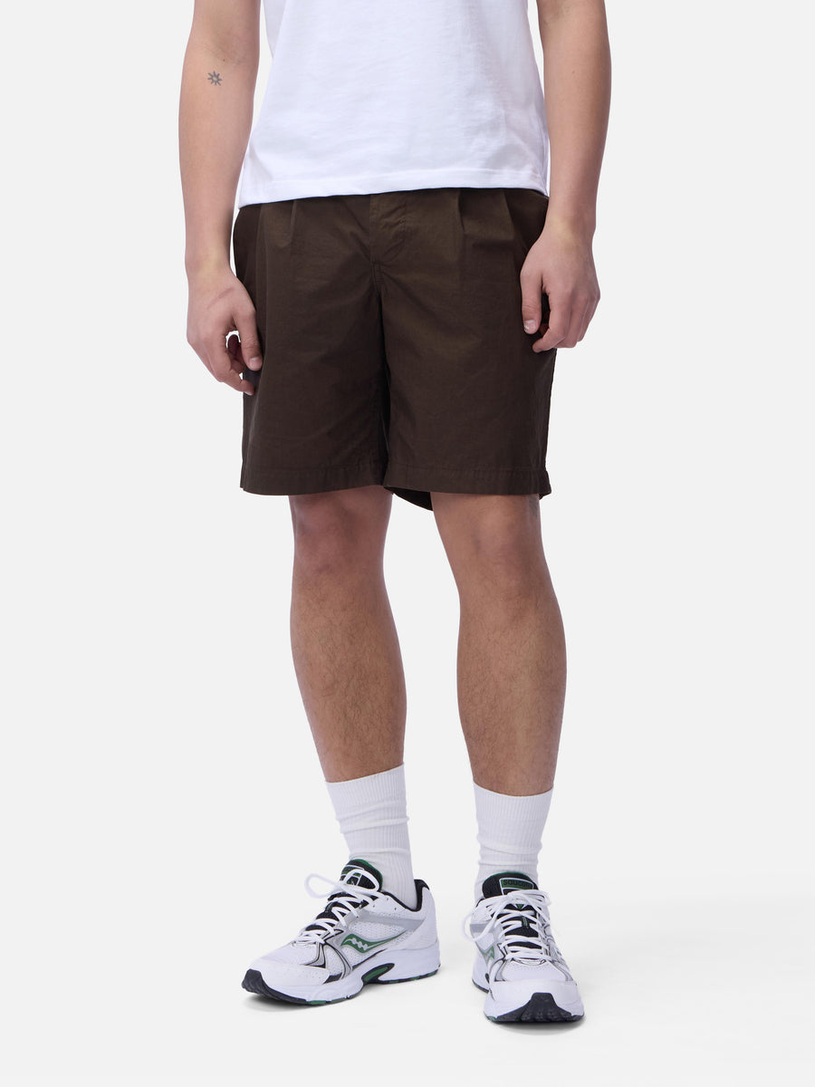 Person wearing brown shorts and white sneakers on a white background
