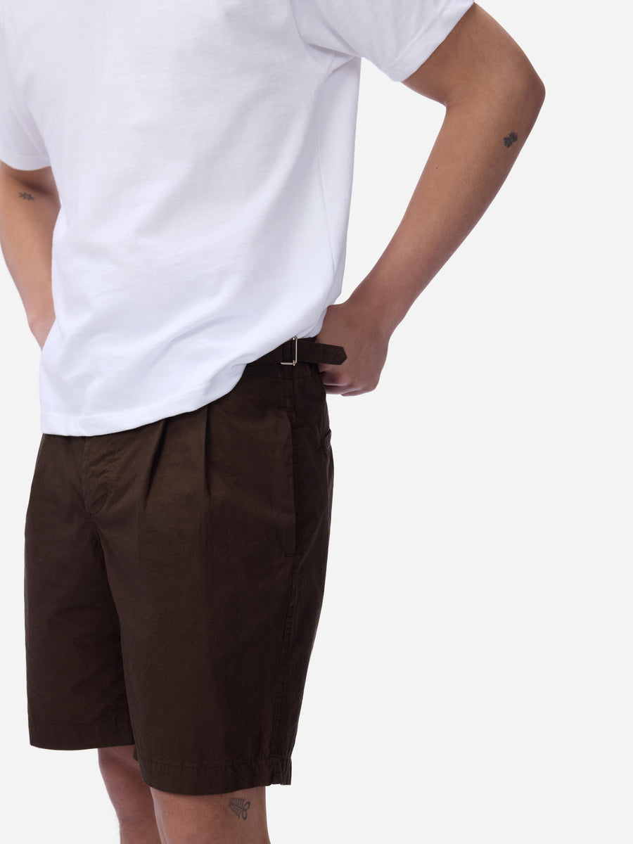 Person wearing brown shorts and a white t-shirt on a plain background